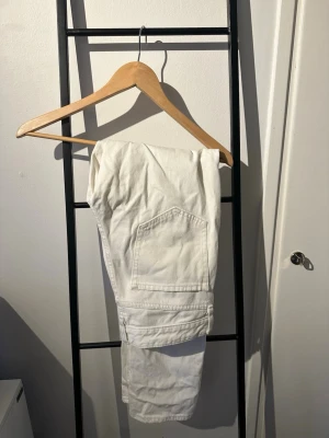 Vita jeans - Säljer ett par vita jeans med rak passform och stängs med knapp och dragkedja. Materialet är kraftigt bomullstyg som ger en clean och fräsch look. storlek 29/32