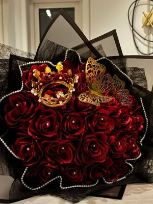 Bukett med röda konstrosor och dekoration - Säljer en lyxig bukett med mörkröda konstgjorda rosor, dekorerad med en guldfärgad krona, pärlor och metalliska fjärilar. Buketten är inslagen i svart och transparent papper med pärlband runt. Perfekt som present eller dekoration. OBS!! Förbeställnignsvara. Färger och detaljer efter önskemål finns. Hör av er för ytterligare information!