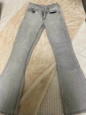 Ljusgrå bootcut jeans från Lager 157 - Säljer ett par ljusgrå jeans från Lager 157 med bootcut passform. Jeansen har klassisk femficksdesign, normal midja och är tillverkade i denim. Perfekta för dig som gillar en avslappnad men trendig stil.