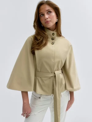 Beige poncho trenchcoat med vida ärmar - Stilren beige trenchcoat från Gina Tricot med vida ärmar, hög krage med knappar och knytskärp i midjan. Jackan har en kortare modell och är tillverkad i ett slätt tyg. Den är köpt nyligen men kommer inte till användning.