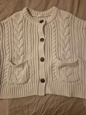 Krämvit kabelstickad kofta med fickor S - Favorit kofta börjar bli sliten men vill ge den sista användning innan den slängs. Kort modell. 