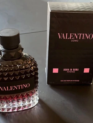 Valentino Uomo Born In Roma Intense EdP - Valentino Uomo Born In Roma Intense Eau de Parfum har en cool, lyxig flaska i svart och mörkrosa med nitar och rutmönster. Märket syns tydligt på etiketten. Doften är intensiv och exklusiv, perfekt för dig som gillar statement-parfymer. Priset kan diskuteras i dm. 