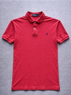 Polo Ralph Lauren Polo Shirt – Classic Red – M - Klassisk Polo Ralph Lauren polo shirt i röd färg med den ikoniska Polo Pony-loggan broderad på bröstet.  En tidlös piké som passar perfekt för en clean casual eller preppy look.  Detaljer: • Polo Ralph Lauren • Storlek M • Mycket bra skick • Klassisk polokrage med knappar • Broderad Pony-logga • Röd färg  Perfekt till jeans, chinos eller shorts.  📦 Skickas snabbt 💬 Hör gärna av dig vid frågor
