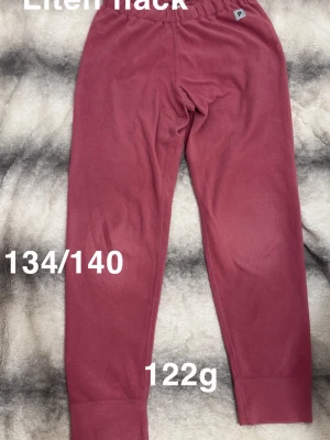 Mörkrosa fleecebyxor med resår - Mysiga mörkrosa fleecebyxor med resår i midjan och breda muddar vid bensluten. Perfekta för chill dagar hemma eller när du vill ha det extra bekvämt. 🌸 Plattare på knäna. Liten fläck. storlek 134/140