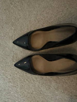 Svarta lackpumps med spetsig tå - Säljer ett par klassiska svarta pumps från Asos i glansigt lackmaterial. Skorna har spetsig tå och hög klack som ger en elegant siluett. Använt 1 gång säljs då den är för stor på mig. Pris kan diskuteras 