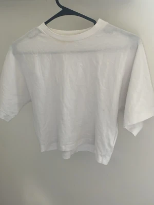 Vit croppad t-shirt i bomull - En basic vit croppad t-shirt med rund hals och korta ärmar. Perfekt till jeans eller kjol för en enkel och clean look. Tillverkad i mjuk bomull som känns skön mot huden.