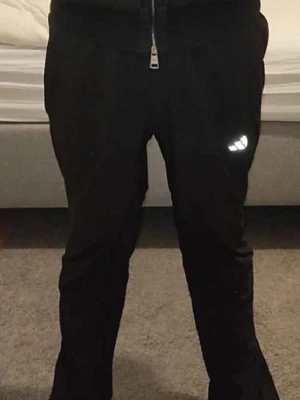 Svarta mjukisbyxor från Adidas - Säljer ett par svarta mjukisbyxor från Adidas med klassisk logga på vänster lår. Byxorna har dragsko i midjan och smal passform. Perfekta för chill eller träning, riktigt sköna och stilrena.