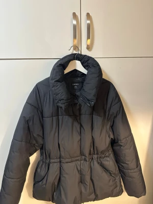 Svart pufferjacka från Lindex - Jacka från lindex med justerbar indragning i midjan.