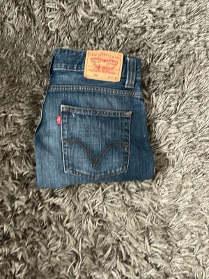 Blå Levi's jeans 506 - Klassiska blå jeans från Levi's. Jeansen har en snygg tvätt med lätt slitning och den ikoniska röda Levi's-lappen på bakfickan. Tillverkade i slitstark denim, perfekta för en avslappnad och cool stil. 