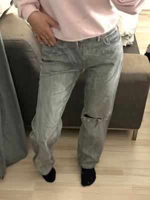 Washed gray jeans med raka ben - Säljer ett par gråa jeans med hög midja och slitning på ena knät. Jeansen har klassisk femficksdesign och raka ben. Perfekta för en avslappnad och trendig look. Använda endast en gång så i nytt skick! 