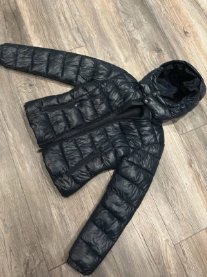 Svart pufferjacka lager157 - Mörkblå glansig jacka från lager 157, storlek xs, inga lappar kvar tyvärr. Använd några gånger men inga defekter. 