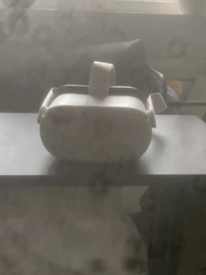 Oculus Quest 2 VR-headset vitt - Säljer ett Oculus Quest 2 VR-headset i vitt med justerbart huvudband och mjuk vaddering runt ögonen. Glasögonen har en modern, rundad design och är tillverkade i plast med tygband. Perfekt för dig som vill uppleva VR-spel och appar på riktigt.