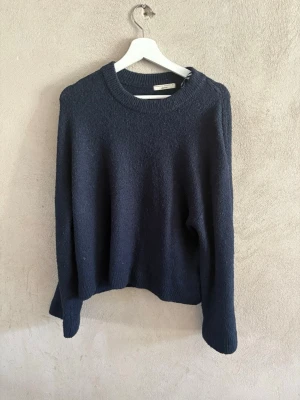 Mörkblå stickad tröja Arket - Mysig mörkblå stickad tröja från Arket med rund halsringning och långa ärmar. Tröjan har en enkel, klassisk design och är tillverkad i ett mjukt material som passar perfekt till kyligare dagar.