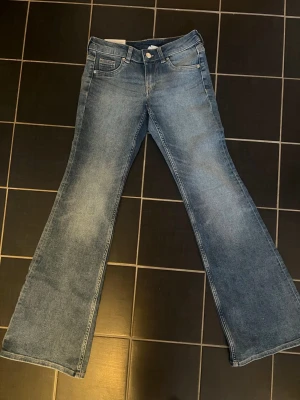 Blå bootcut jeans lågmidja - Säljer ett par klassiska blå bootcut jeans med utsvängda ben och låg midja. Helt nya med prislappen kvar.