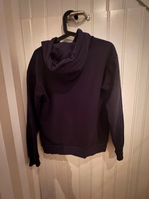 Mörkblå hoodie Gina Tricot  - Snygg mörkblå hoodie med huva och dragsko. På bröstet står det 'MA CHÉRIE' i glittriga stenar som ger en cool touch. Hoodien har ribbade muddar vid ärmar och midja. Perfekt för dig som vill ha en enkel men trendig look.