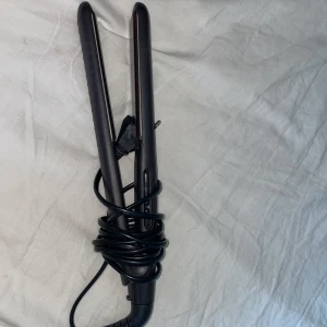 Plattång - Säljer en svart plattång med digital display och temperaturinställning. Plattången har knappar för att justera värmen och en on/off-knapp. Perfekt för att platta håret.