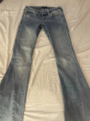 Bootcut jeans från True Religion - Säljer ett par ljusblå bootcut jeans från True Religion med snygga kontrastsömmar och detaljerade bakfickor med lock och silverknappar. (Pris kan diskuteras)