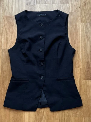 Svart kostymväst från gina tricot - Stilren svart kostymväst från gina tricot med. Västen har en figurnära passform och är ärmlös.✨