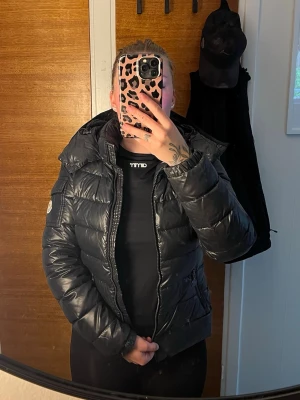 Svart pufferjacka från Moncler - Snygg svart pufferjacka från Moncler med glansig finish och klassisk logga på ärmen.                           Storlek XS/S