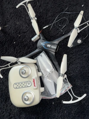 Syma X5A quadcopter med kontroll (drönare) - Säljer en svart och vit Syma X5A quadcopter med tillhörande vit fjärrkontroll och extra propellrar. Dronen har fyra armar med skydd och är tillverkad i plast. Perfekt för dig som vill testa att flyga drönare och göra coola manövrar.