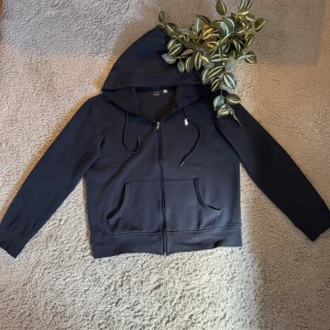 Mörkblå hoodie från Polo Ralph Lauren - Mörkblå Ralph Lauren zip-up i riktigt fint skick 💙  Sitter sjukt nice och passar till allt 🔥   Inga tecken på användning och dragkedjan funkar perfekt ✨ Är 177 och den är lite kort i ärmarna👍 Storlek: S passar ungefär 168-175 Pris kan diskuteras 💸   Snabb frakt 🚚   Skriv vid frågor eller fler bilder 📩