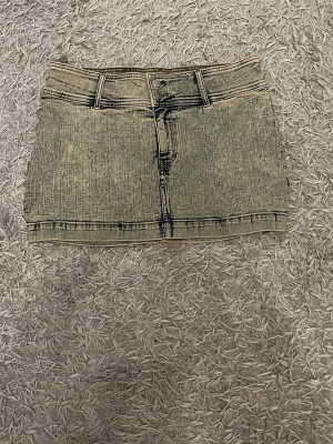 Beige jeanskjol med fickor - Trendig jeanskjol i minilängd med klassiska fickor både fram och bak samt hällor för skärp. Kjolen har en rak passform och stängs med knapp och dragkedja framtill. 