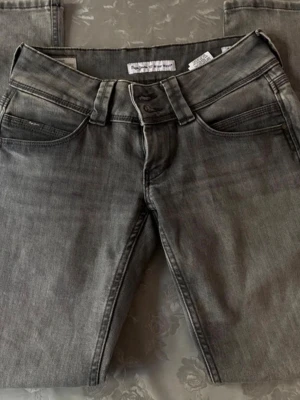 Grå jeans från Pepe Jeans - Snygga grå jeans från Pepe Jeans med klassisk femficksdesign och raka ben. Jeansen har en cool tvättad look och tydliga sömmar. 