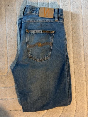 Nudie Jeans 29/32 - Säljer dessa riktigt schyssta Nudie jeansen! Jeansen är raka i benen och riktigt snygga och perfekt nu till våren. Dom är i hyffsat skick och storlek W29 L32! Hör av er vid minsta fundering eller för fler bilder!