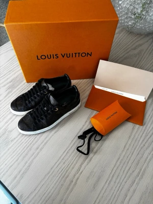 Louis Vuitton monogram sneakers - Snygga Louis Vuitton sneakers i svart med klassiskt monogrammönster och vita sulor. Skorna har svarta skosnören och guldfärgade detaljer vid snörningen. Tillverkade i läder med lyxig känsla och ikonisk design. Skorna är i fint skick utan defekter. Storlek 36 men passar även om man har 37. Kvitto finns, samt allt följer med vid köp som man fick från butiken. 