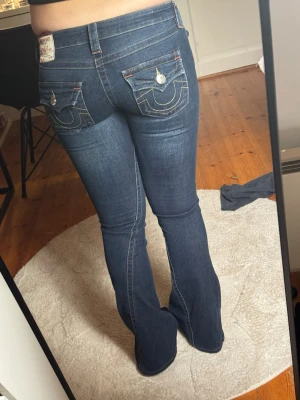 Mörkblå true religon W24 - Snygga mörkblå jeans från True religon. Säljer dom eftersom de ej passar längre 💗 Jeansen har låg midja och utsvängda ben. Det är storlek W24 och modellen heter Joey Low Rise Flare. De är i mycket bra skick och har inget slitet. 
