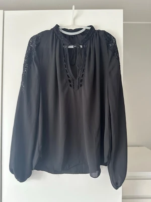 Svart blus - En fin svart blus med fin spets på axlarna och fina detaljer.