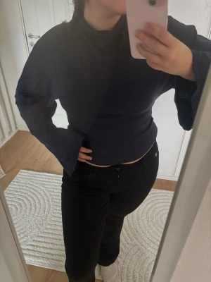 Mörkblå croppad långärmad topp - Snygg mörkblå croppad topp med långa ärmar och hög hals. Toppen har en tight passform och är tillverkad i ett mjukt, stretchigt material som sitter skönt mot kroppen. Perfekt att styla med jeans eller kjol.