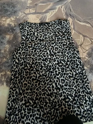 Leopardmönstrad ärmlös topp Vero Moda - Säljer en snygg ärmlös topp från Vero Moda med leopardmönster i svart och beige. Toppen har v halsringning och är tillverkad i ett lätt, mjukt material som känns skönt mot huden. Perfekt för dig som vill sticka ut lite extra.