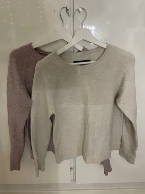 Vit/beige, rosa/lila stickad tröja med rund hals - Rosa/lila, vit/beige stickad tröja med rund halsringning och långa ärmar. Tröjan har en enkel och stilren design med ribbstickade muddar vid ärmslut. Inte världens bästa kvalité då dom är rätt så använda.