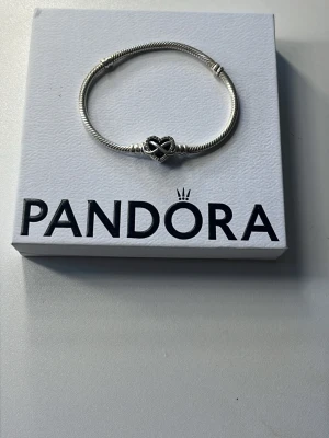 Pandora moments berlockarmband silver  - Pandora berlockarmband i nyskick. Köpt förra våren och användes endast i någon vecka. Hjärtlänk med oändlighetssymbol i och gravering på baksidan, perfekt till mors dag eller liknande.💞Orginalpris 899