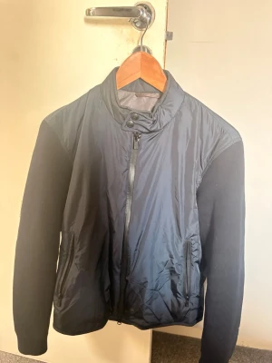 Massimo dutti cardigan marinblå - Snygg marinblå massimo dutti cardigan med hög krage och dragkedja framtill. Jackan har två sidofickor med dragkedja och är tillverkad i en mix av polyester och stickat material på ärmarna. Perfekt för dig som vill ha en stilren och enkel jacka. (OBS, sitter som storlek S) jag bär vanliga fall storlek S o denna storlek M sitter perfekt