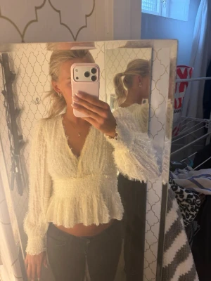 Vit fluffig omlottopp med volang - Superfin vit topp med omlott-skärning och volang nertill, från Nakd i storlek 36. Långärmad med fluffig, stickad känsla och v-ringad hals. Perfekt för dig som vill ha en söt och trendig look.