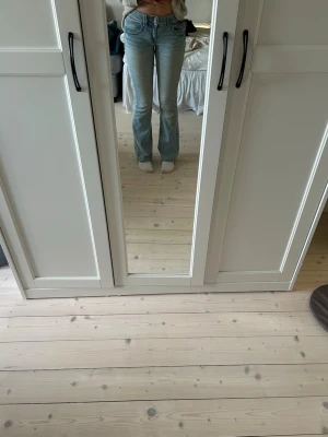 Ljusblå bootcut jeans - Säljer ett par ljusblå bootcut jeans med mid/låg midja.