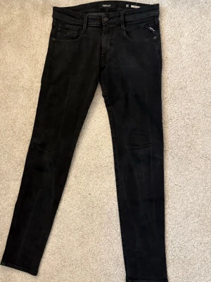  jeans från Replay - Snygga svarta jeans från Replay med klassisk femficksdesign och dragkedjedetalj på myntfickan. Jeansen har smal passform och är tillverkade i stretchigt material för extra komfort. Perfekta för en trendig och stilren look.