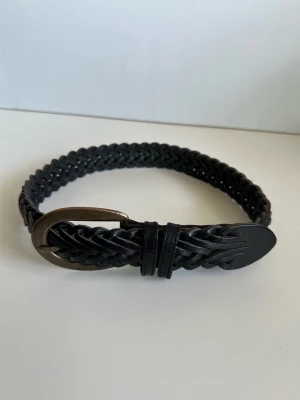 MEXX - Svart flätat skärp i 100% läder - storlek XS / S - Stilrent svart flätat bälte / skärp från MEXX i 100% äkta läder / skinn. Tidlös modell med spänne i metall och oval ände, flätat på åtta sammanhängande remmar i robust läder. 3,5 cm brett och 81 cm långt, passar alla midjemått upp till 73cm, motsvarande storlek XS - S. Klassiskt kvalitativt läderväst som kommer hålla år efter år. Mycket gott skick, som ny!