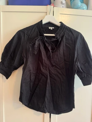 Svart blus med knyt från Twist & Tango - Blus från Twist & Tango med knytning vid halsen. B