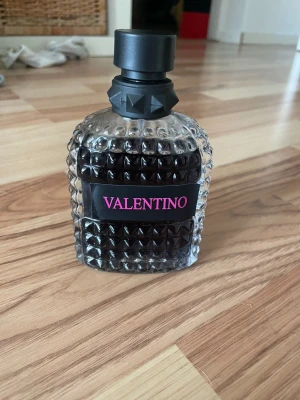 Valentino parfym med nitar - Säljer en parfym från Valentino i en cool, genomskinlig glasflaska med nitar och svart lock. Flaskan har en svart etikett med rosa text. Perfekt för dig som gillar exklusiva och trendiga dofter.