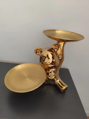 Guldfärgad björnformad dekoration - Unik dekoration i form av en björn med två fat, helt i guldfärgad metall. Perfekt som smyckesfat eller för småprylar. Modern och lekfull design som sticker ut i rummet.