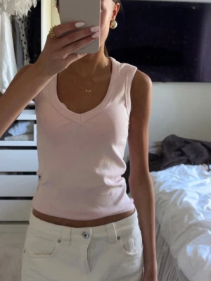 Ljusrosa ribbad topp - Säljer en ljusrosa ribbad topp från Gina tricot med snygg V-ringning. Storlek s, använd 1 gång! Som ny💕