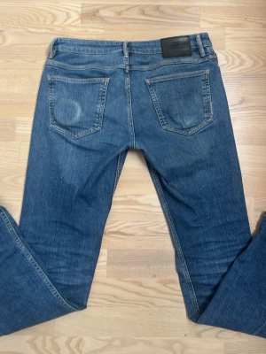 Blå Neuw jeans - Säljer ett par klassiska blå jeans från Neuw med slim passform och fem fickor. Jeansen har en snygg tvättad look, normal midja och detaljer i silverfärgad metall. Materialet är mjukt denim i bomull. Perfekta för en avslappnad stil.