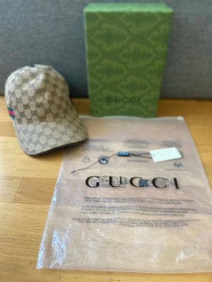 Beige keps från G med monogram - Snygg beige keps från Gmed klassiskt gg-monogram över hela kepsen och en grön-röd rand på sidan. Kepsen har böjd skärm och justerbar passform. Kommer med originalförpackning och tagg.jag är seriös jag lovar jag gillar inte den här färgen på Dena kepsen så köp i så fall om ni är intresserade jag gillar bara svarta😎🙏📦postar inom cirka 45 min eller 24 timmar📦om ni it vill ha den då säljer jag den till min kompis jag måste bli av med den kepsen inom en månad 