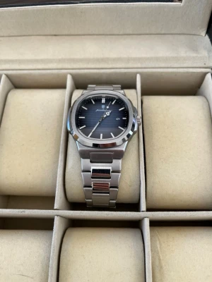 Ekstrand PP Blå/Silver - Stilren klocka med blå urtavla och datumvisning. Boetten och länken är i blankt silverfärgat metall, vilket ger en modern och clean look. Perfekt accessoar för dig som gillar minimalistisk design.