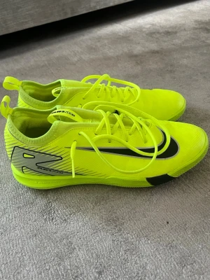 Nike Mercurial Futsal  - Säljer ett par Nike Mercurial futsal i neon-gult med svarta detaljer och logga. Skorna har låg profil, snörning och är tillverkade i ett lätt syntetmaterial för bästa känsla på planen. Perfekta för dig som vill sticka ut och ha bra grepp på hårt underlag.