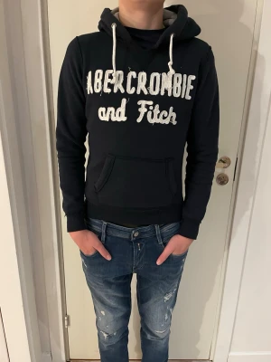 Marinblå hoodie Abercrombie & Fitch - Snygg marinblå hoodie från Abercrombie & Fitch. Modellen är 179 cm. Storlek S 