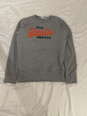 Superdry crewneck tröja - Grå | storlek S | mörkblå och orange text på framsida